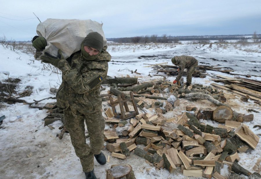A Ukrainian soldier sets up a wooden trench in the snow. 