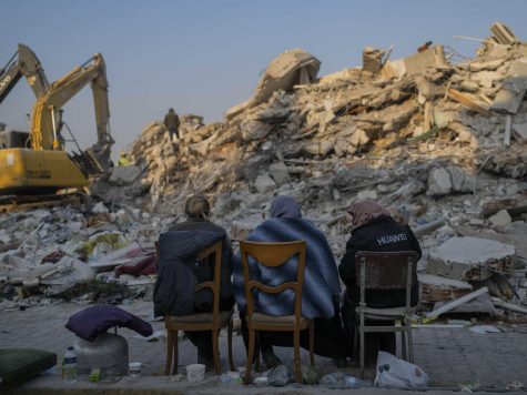 Women sit in front of the rubbles they once called home. 