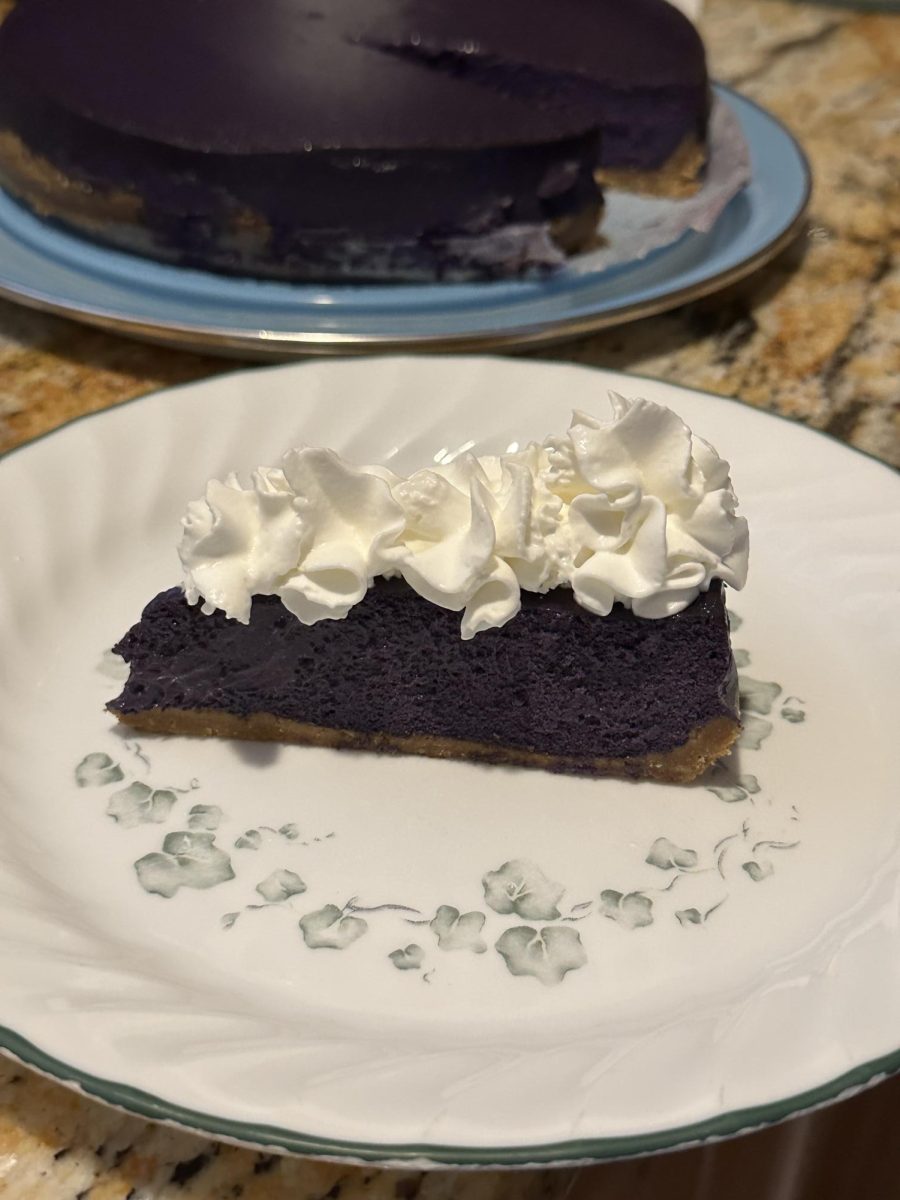 Ube cheesecake topped with whipped cream.