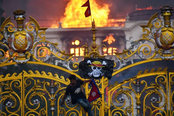 Citizen is shown waving the Straw Hat flag from the Japanese manga and anime series in front of a government complex burning set ablaze.